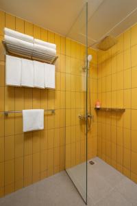 y baño de azulejos amarillos con ducha y toallas. en lyf Malate Manila - Managed by The Ascott Limited, en Manila