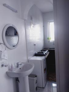 a white bathroom with a sink and a mirror at C.leslie_homes in Bamburi