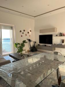 een woonkamer met een glazen tafel en een televisie bij Coralinehaven in Castellammare di Stabia