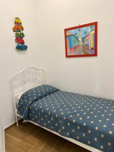 een slaapkamer met een bed met een blauwe deken en een foto bij Coralinehaven in Castellammare di Stabia