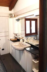 Baño blanco con 2 lavabos y ventana en Rose Apartment, en Aosta