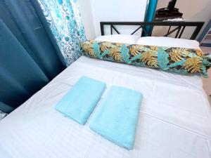 a white bed with two blue towels on it at Blue Diamond Staycation beside Enchanted Kingdom in Santa Rosa