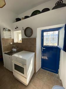 a kitchen with a white stove and a blue door at Sea Esta Serifos Stylish Family Home, Sea View in Serifos Chora