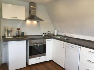 een keuken met witte kasten en een fornuis met oven bij Berghaus 2 komfortable Wohnungen für bis zu 7 Personen - Familie - Wandern - E-Bike - Hunde - E-Ladesäule - WiFi in Schmallenberg