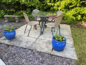 um pátio com uma mesa, cadeiras e plantas em The Annexe em Felton
