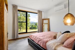 a bedroom with a bed and a large window at Gan Eden Retreat-Byron bay , luxuries escape in Mullumbimby
