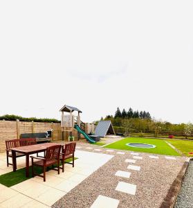 a patio with a table and benches and a playground at Robins Cottage 