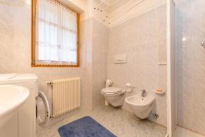 a white bathroom with a toilet and a sink at Casa Soreje in Mazzin +18 photos