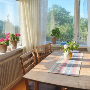 einen Holztisch mit Stühlen und Blumen am Fenster in der Unterkunft Cottage with sea view, Kattviksvägen in Båstad