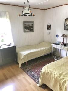a bedroom with two beds and a desk and a window at Cottage with sea view, Kattviksvägen in Båstad