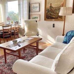 ein Wohnzimmer mit 2 weißen Stühlen und einem Tisch in der Unterkunft Cottage with sea view, Kattviksvägen in Båstad