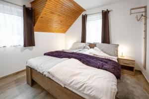 Zgornje Gorje的住宿－Apartmaji Koza，一间卧室设有一张带木制天花板的大床