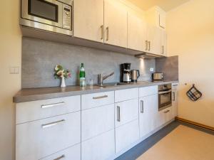 eine Küche mit weißen Schränken und einer Mikrowelle in der Unterkunft Dünenpark Binz - Komfort Ferienwohnung mit 1 Schlafzimmer und Terrasse im Erdgeschoss 118 in Binz