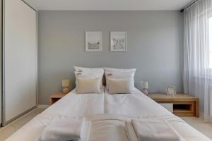 a white bedroom with a large white bed with pillows at Downtown Apartments Seaside Awiator in Gdańsk