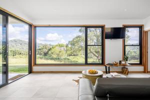 Una sala de estar con un sofá y grandes ventanales. en Gan Eden Retreat-Byron bay , luxuries escape, en Mullumbimby