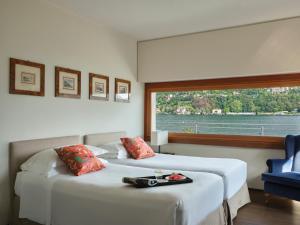 two beds in a room with a large window at Hotel Villa Flori in Como