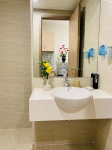 a bathroom with a sink and a mirror and flowers at Vinhomes Smart City Tây Mỗ Nam Từ Liêm in Hanoi