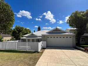 a white house with a fence and a garage at Beachy Vibes in Karrinyup in Perth