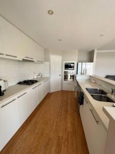 a kitchen with white cabinets and a wooden floor at Beachy Vibes in Karrinyup in Perth