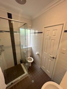a bathroom with a toilet and a glass shower door at Beachy Vibes in Karrinyup in Perth