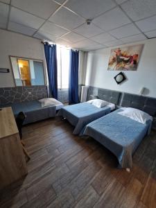 a bedroom with two beds and a couch and a mirror at Hôtel du Nord in Cannes