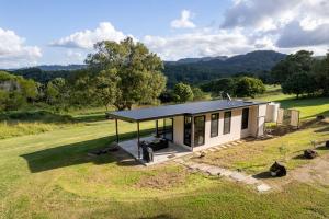 a small house with a black roof in a field at Gan Eden Retreat-Byron bay , luxuries escape in Mullumbimby