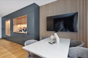 ein Esszimmer mit einem weißen Tisch und einem TV in der Unterkunft ANYTIME - Rohrbach Apartments in Friedrichshafen