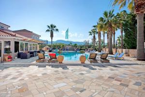 a patio with chairs and a pool with palm trees at Paradise Apartment 1 in Laganas