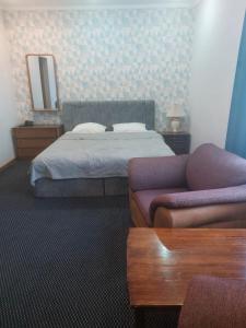 a bedroom with a bed and a couch and a mirror at Victoria Hotel in Aktau