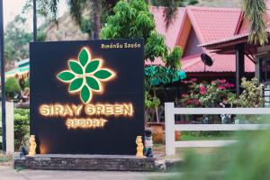 una señal para un resort verde junto a una valla blanca en Siray Green Resort, en Phuket