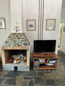 a living room with a tv and a stone fireplace at Elia Home in Lefkogeia