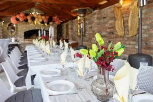 una sala da pranzo con tavoli bianchi, sedie bianche e fiori di Holiday Home TimeOut Bizovac a Bizovac