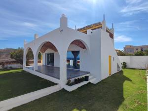 a white house with a yard with green grass at Maison vue mer, île de Zembra et montagne en Tunisie - Elhaouaria in El Haouaria