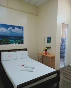 a bedroom with a white bed with a picture on the wall at WJV INN CONSOLACION in Tugbongan