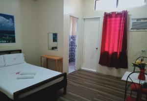 a bedroom with a bed and a red curtain at WJV INN CONSOLACION in Tugbongan