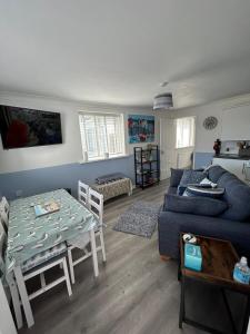 uma sala de estar com um sofá azul e uma mesa em Ruby's Den em Carbis Bay