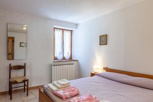 1 dormitorio con cama, silla y espejo en The Dormouse - Il Ghiro, en Casola in Lunigiana