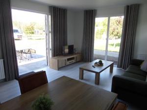 a living room with a table and a couch and a television at Vakantiepark Camping de Peelpoort in Asten-Heusden