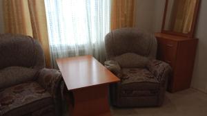 Zimmer mit 2 Stühlen und einem Holztisch in der Unterkunft Victoria Hotel in Aqtau