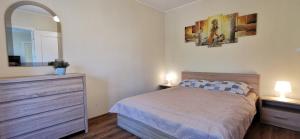 - une chambre avec un lit, une commode et un miroir dans l'établissement Najs Apartamenty z parkingiem, à Sopot