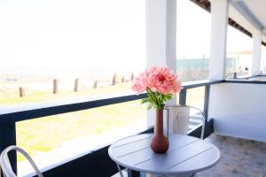un jarrón con flores rosas en una mesa frente a una ventana en Rezident Corbu, en Corbu