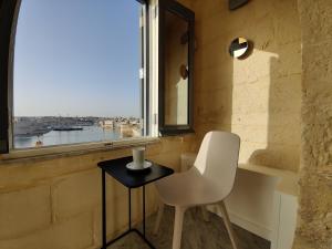 una sedia bianca e un tavolo in una stanza con finestra di Oasis 22 Savynomad Harbour Residences wow Views a La Valletta