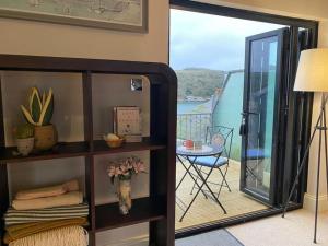 a room with a balcony with a table and a glass door at The Captain’s 4 Bed Penthouse in Fowey +19 photos
