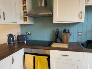 a kitchen with white cabinets and a stove with yellow towels at The Captain’s 4 Bed Penthouse in Fowey
