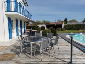 un patio con mesa y sillas junto a una piscina en maison de campagne proche des plages, en Saint-Romain-de-Benet