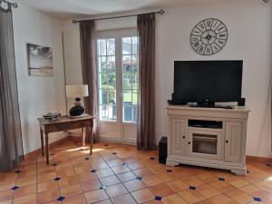 sala de estar con TV y suelo de baldosa. en maison de campagne proche des plages, en Saint-Romain-de-Benet