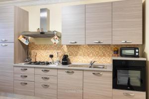 a kitchen with wooden cabinets and a sink and a microwave at House&Villas - Casa Amica in Avola