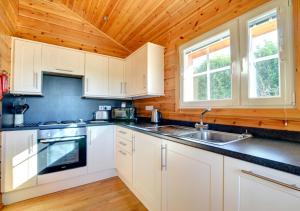 a kitchen with white cabinets and a wooden ceiling at Silver Birch Lodge in Middleton