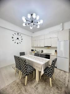 a kitchen with a table and chairs and a clock at Raduga West Cottage 38-4 in Koshkolʼ