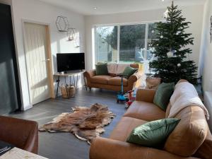 a living room with a couch and a christmas tree at The Stables,Ashley in Ashley